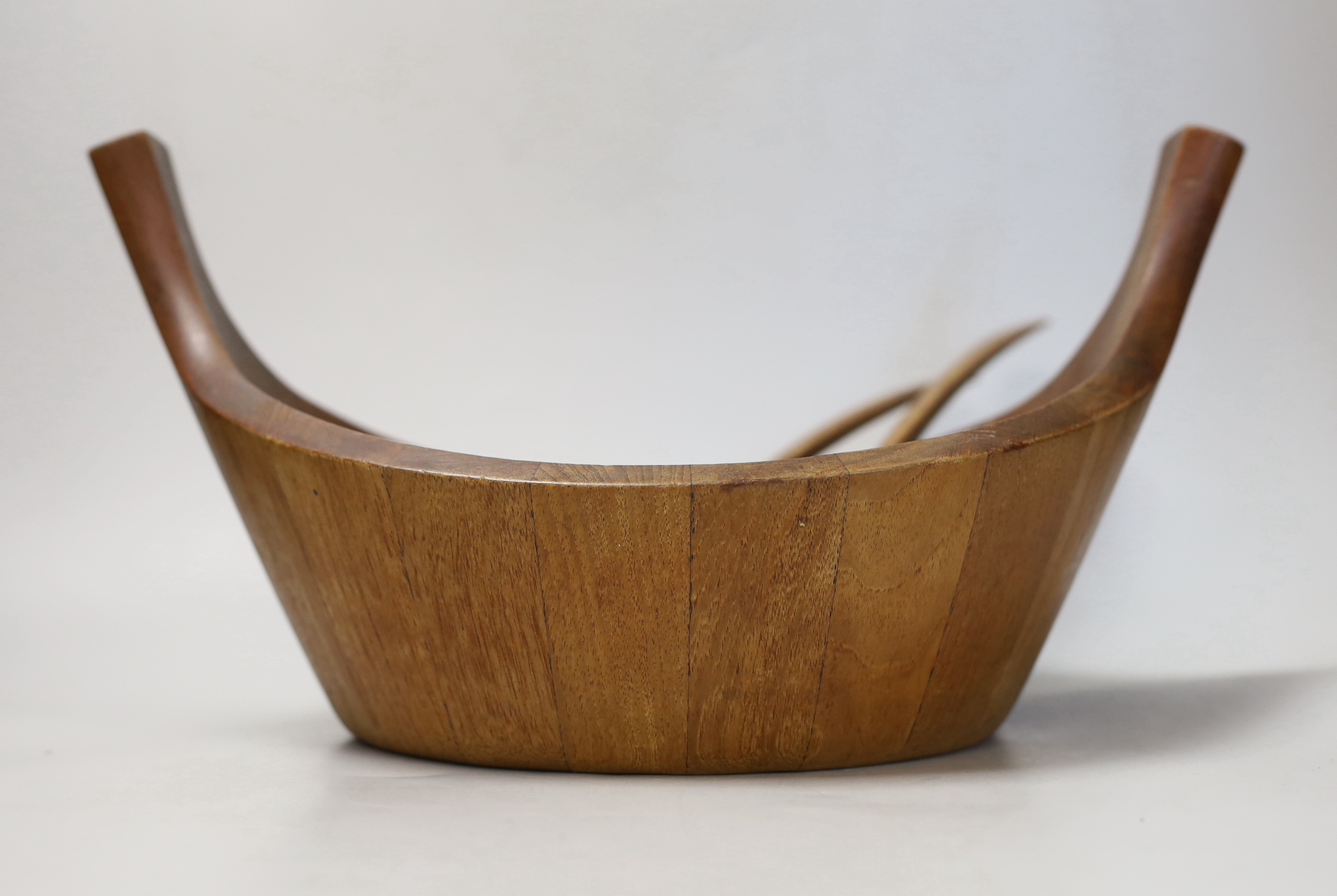 A Jens Quistgaard, for Dansk designs, Danish salad bowl with raised handles and a pair of salad servers, circa 1950's, designed in staved teak, 37cm wide